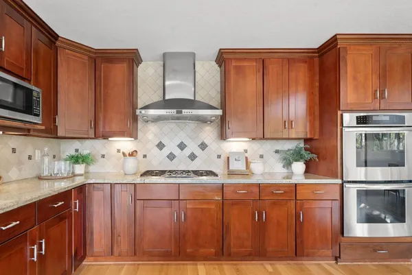 a kitchen with stainless steel appliances granite countertop a stove a sink dishwasher and cabinets with wooden floor