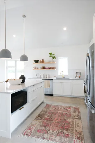 a kitchen with stainless steel appliances granite countertop a sink a stove and a refrigerator