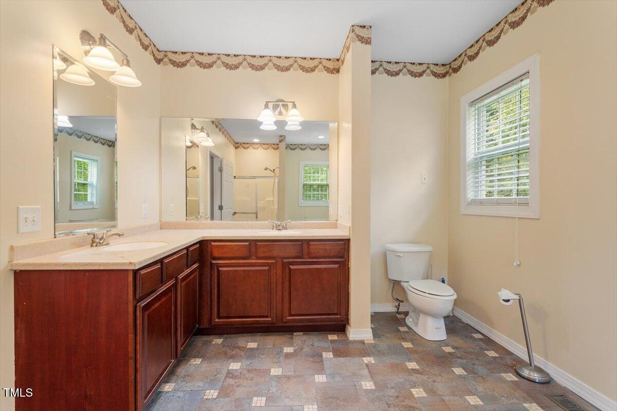 1175 Faulkner Town Road Henderson, NC 27537 - Photo 31 of 48 a spacious bathroom with a granite countertop sink a toilet and a mirror