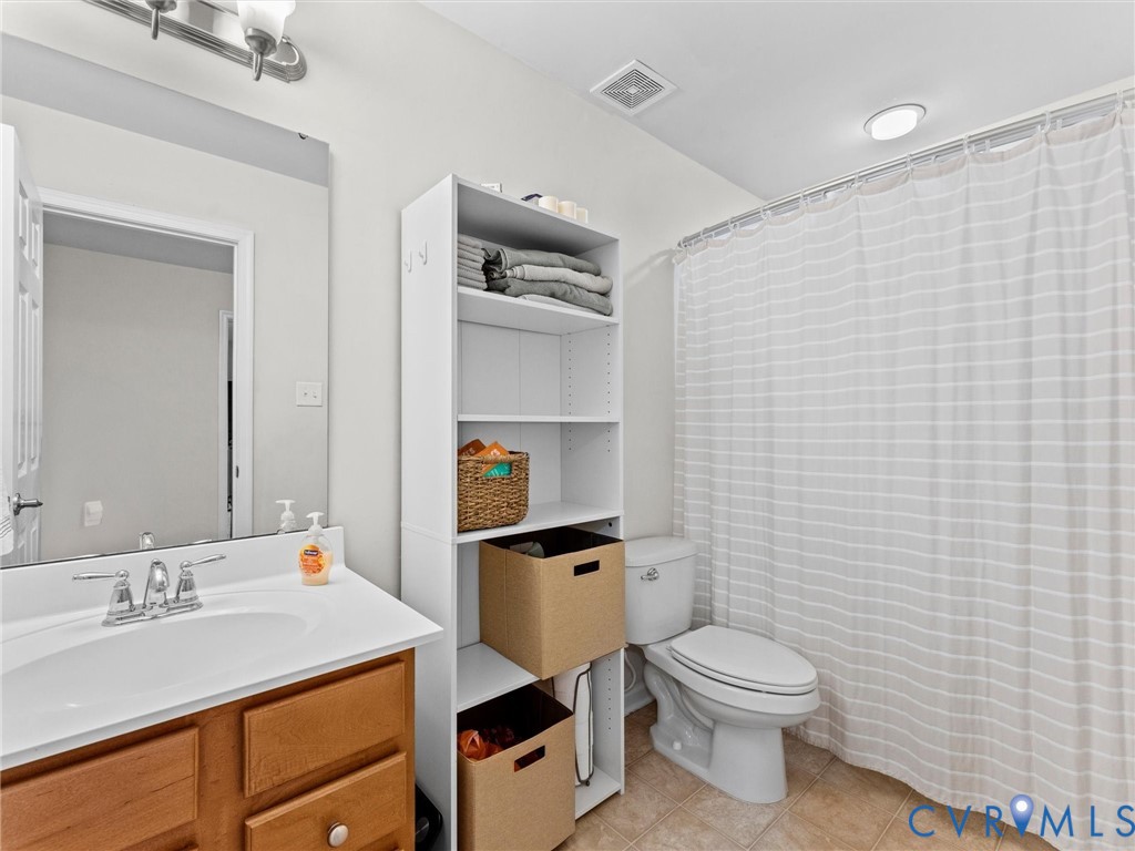 7036 Heartleaf Lane Moseley, VA 23120 - Photo 23 of 28 a bathroom with a granite countertop toilet sink and mirror