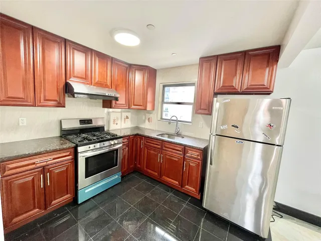 a kitchen with stainless steel appliances granite countertop a refrigerator stove a sink dishwasher and wooden cabinets