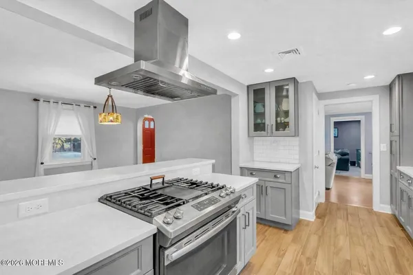 a kitchen with a stove and a wooden floor