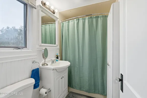 a bathroom with a sink a toilet a mirror and shower curtain