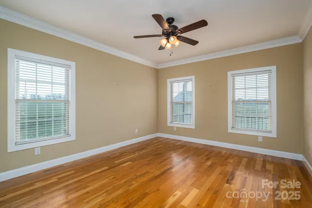 a view of an empty room with a window and wooden floor