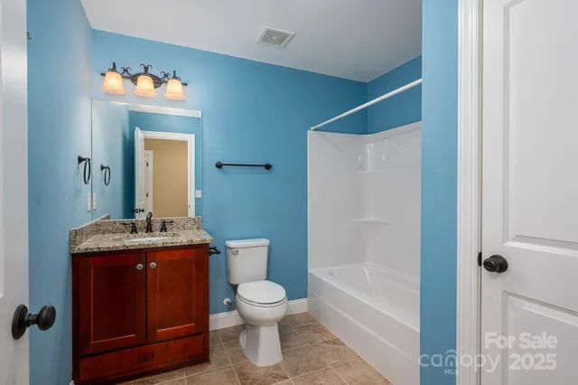 a bathroom with a granite countertop sink a toilet and shower