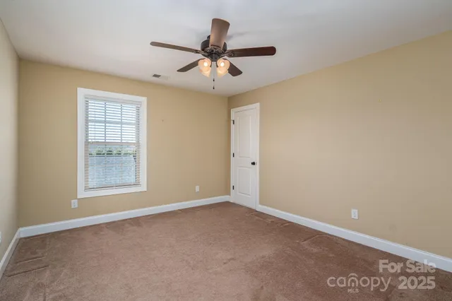 an empty room with ceiling fan and window