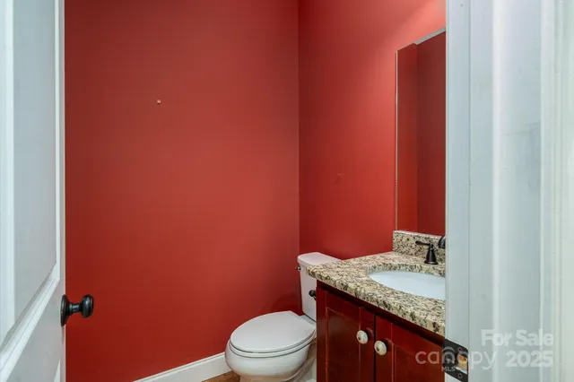 a bathroom with a granite countertop sink and a toilet