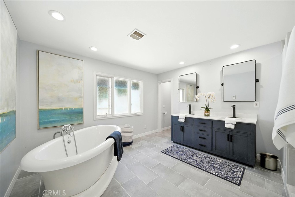 232 7th Street Seal Beach, CA 90740 - Photo 37 of 55 a spacious bathroom with double vanity a window a bathtub and mirrors