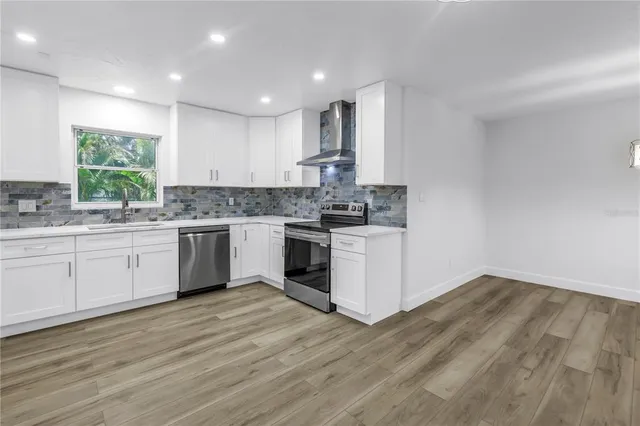 a view of kitchen and empty room with wooden floor