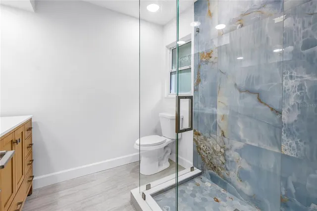 an empty room with wooden floor chandelier fan and windows