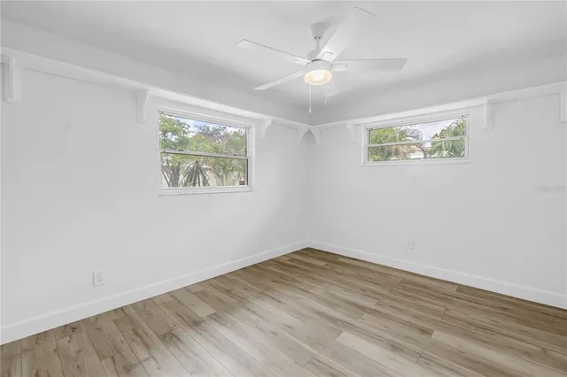 an empty room with wooden floor and window