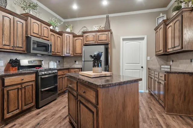 a kitchen with stainless steel appliances granite countertop a stove top oven a sink dishwasher and cabinets with wooden floor
