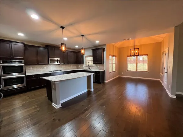 a large kitchen with a center island wooden floor stainless steel appliances and cabinets