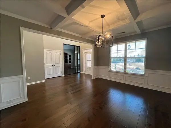 a view of a room with wooden floor chandelier and windows
