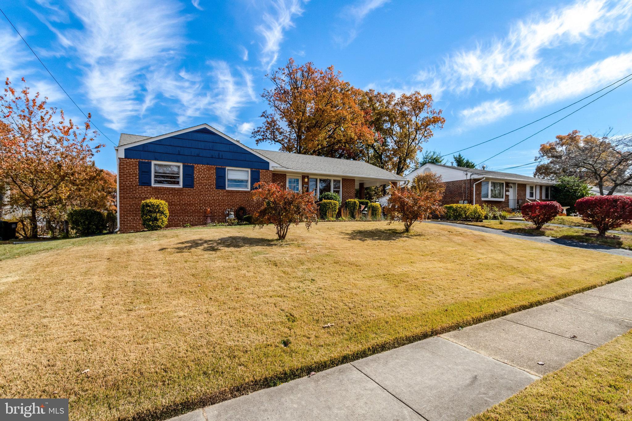 6928 Ruskin Street Springfield, VA 22150 - Photo 2 of 34 a blue swimming pool is in front of a brick house with large trees