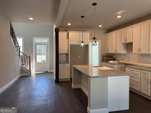a kitchen with stainless steel appliances granite countertop a refrigerator a sink dishwasher a stove and white countertops with wooden floor