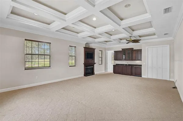 an empty room with kitchen view and windows
