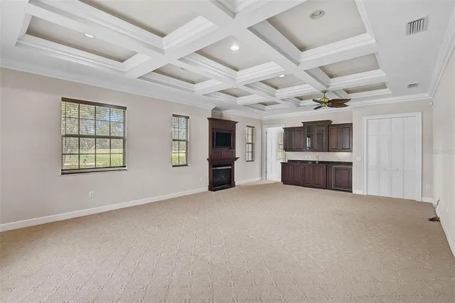 an empty room with kitchen view and windows