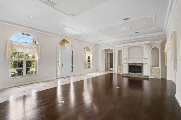 an empty room with wooden floor fireplace and windows