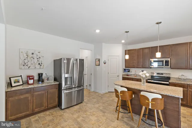 a kitchen with stainless steel appliances a refrigerator a stove a sink a dining table and chairs with wooden floor