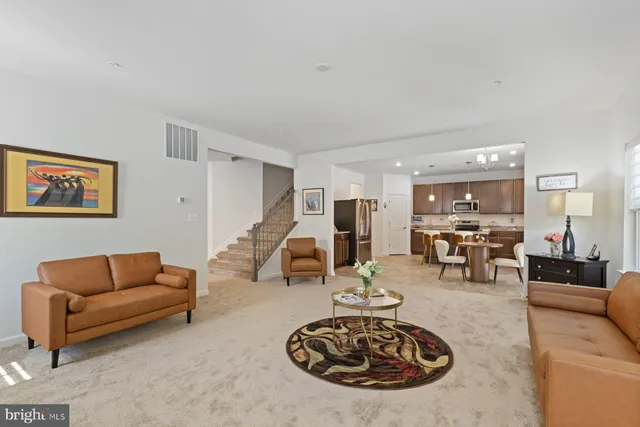 a living room with furniture a table and kitchen view