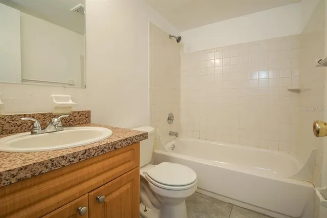 a bathroom with a granite countertop sink toilet mirror and bathtub