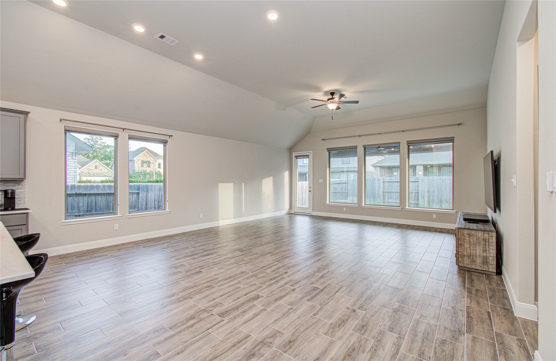 17344 Grand Canyon Road Conroe, TX 77302 - Photo 30 of 49 Spacious, open-concept living room with high ceilings, recessed lighting, and large windows allowing plenty of natural light. The room features wood-look tile flooring and a ceiling fan, creating a bright and modern atmosphere.