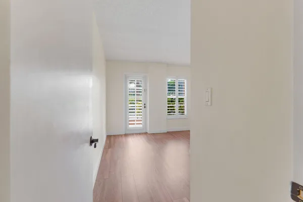 a view of an empty room with a window and wooden floor