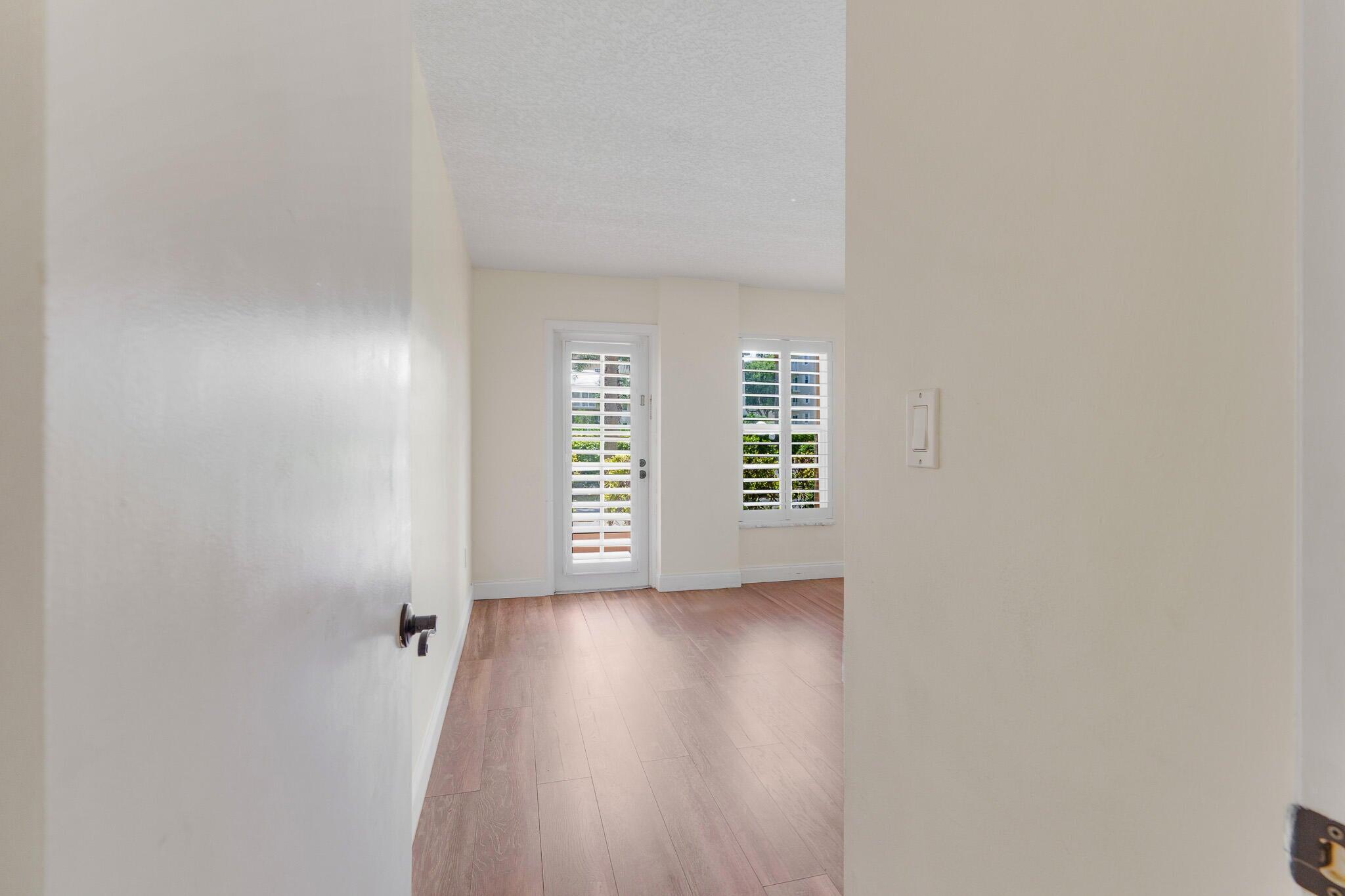 951 De Soto Road, Unit 130 Boca Raton, FL 33432 - Photo 17 of 38 a view of an empty room with a window and wooden floor