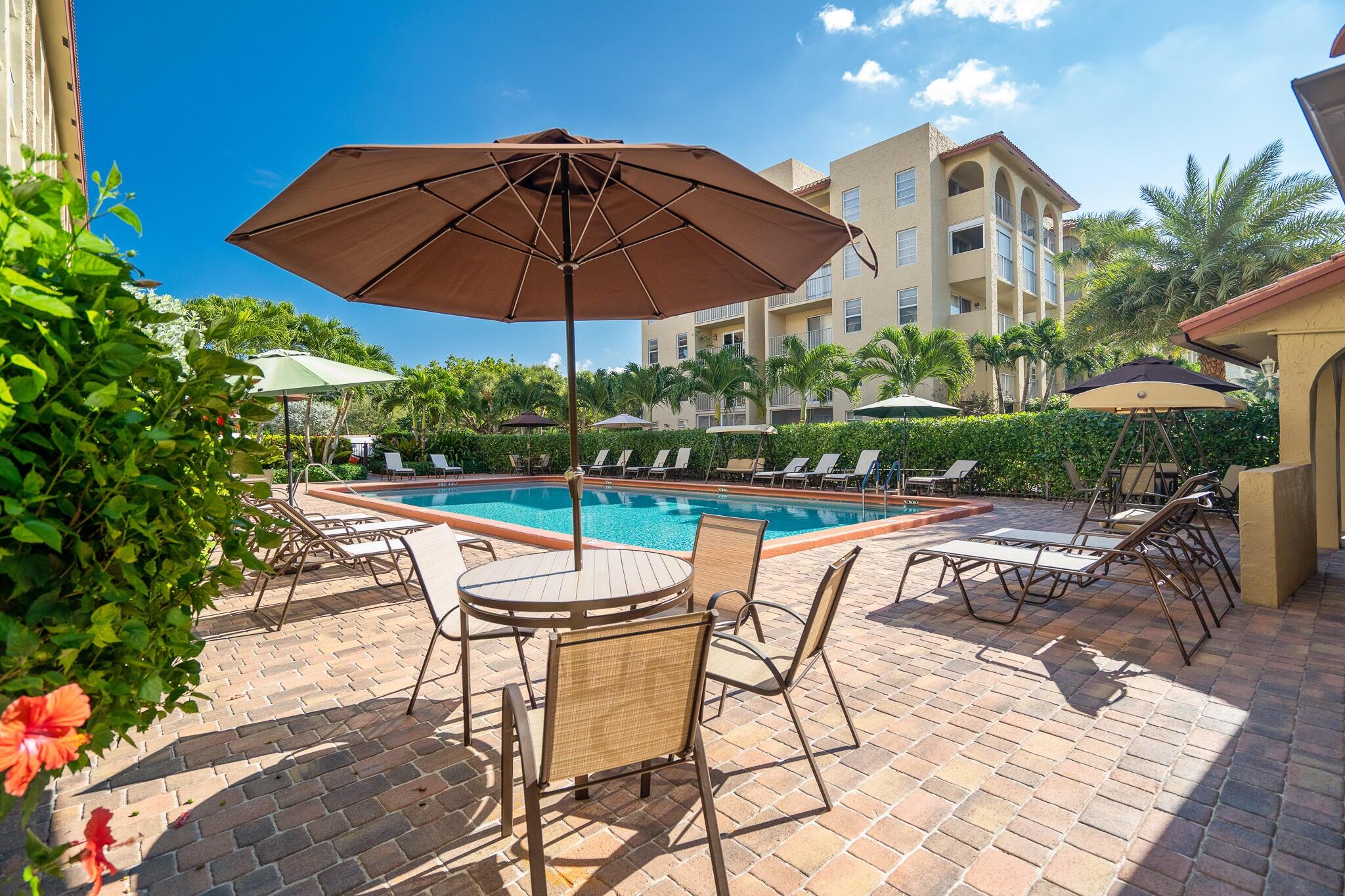 951 De Soto Road, Unit 130 Boca Raton, FL 33432 - Photo 26 of 38 a view of a chairs and table in the patio and a garden