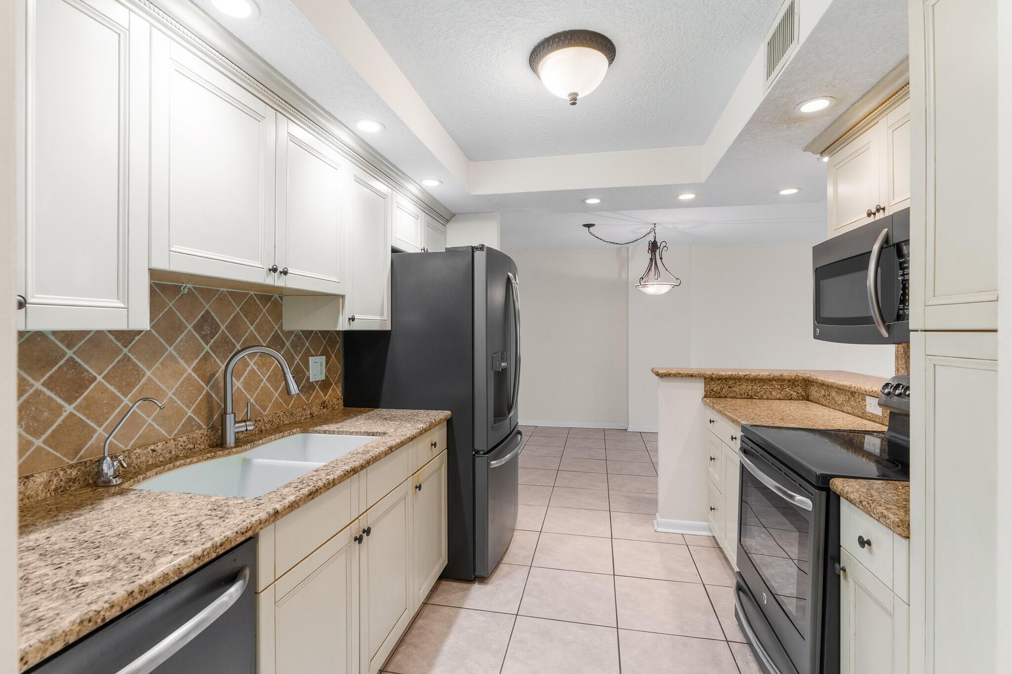 951 De Soto Road, Unit 130 Boca Raton, FL 33432 - Photo 9 of 38 a kitchen with stainless steel appliances granite countertop a sink stove and refrigerator