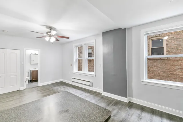 a view of an empty room with a window and wooden floor