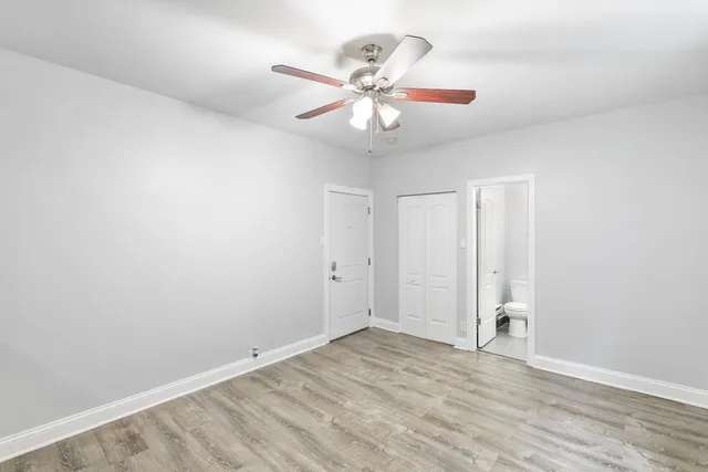 an empty room with wooden floor fan and windows