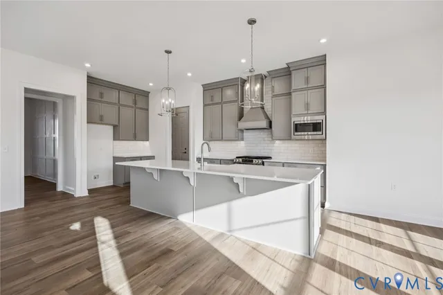 a large white kitchen with a stove a sink dishwasher and a refrigerator with wooden floor