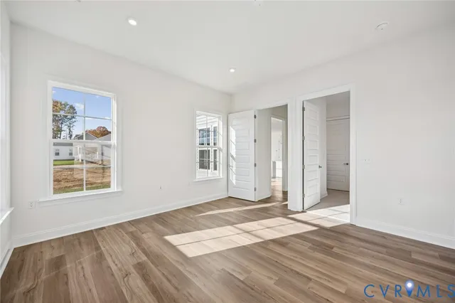 an empty room with wooden floor and windows