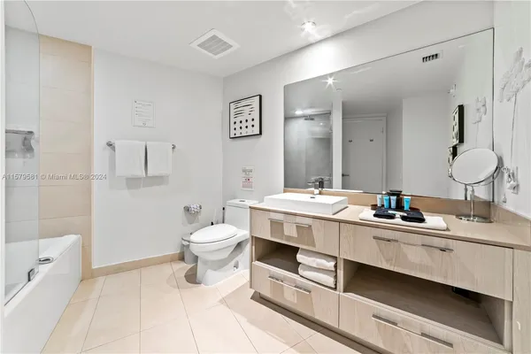 a bathroom with a double vanity sink toilet mirror and shower