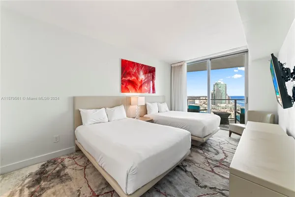 a bedroom with two beds and a flat screen tv