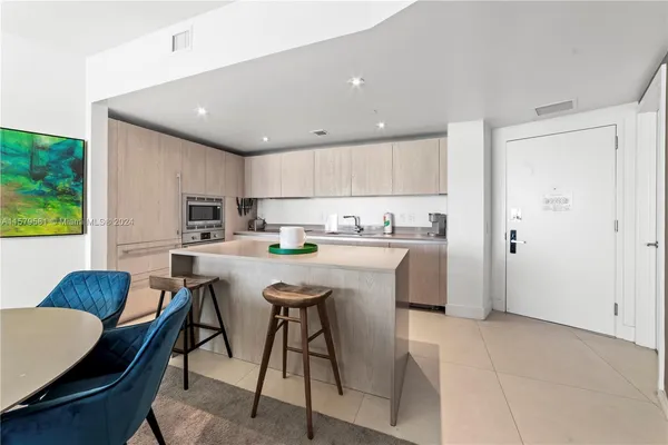 a kitchen with stainless steel appliances granite countertop a sink a stove a refrigerator cabinets and chairs