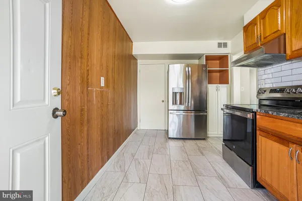 a kitchen with stainless steel appliances granite countertop a refrigerator and a stove top oven