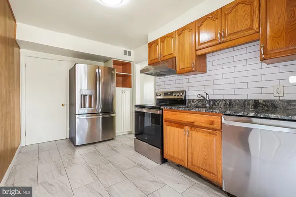 a kitchen with stainless steel appliances granite countertop a refrigerator a stove and a sink