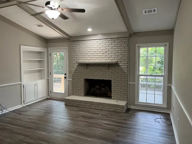 a view of a livingroom with a fireplace window and wooden floor