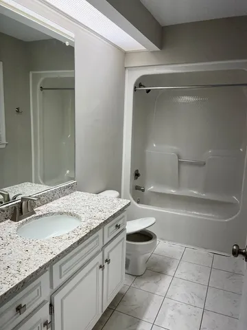 a bathroom with a granite countertop sink a toilet and bathtub