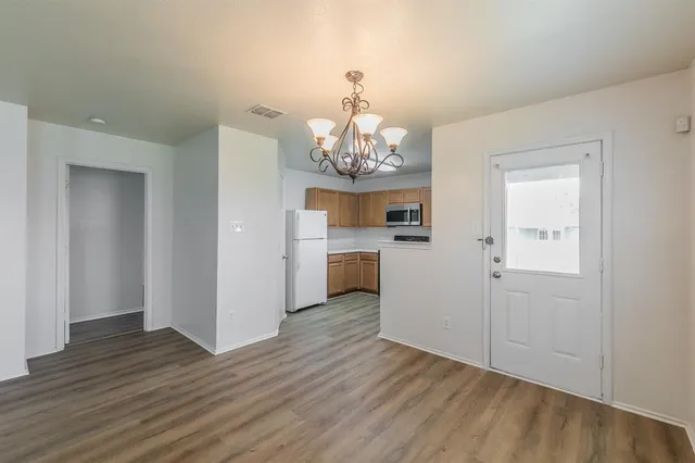 a view of a kitchen with an empty room and chandelier wooden floor