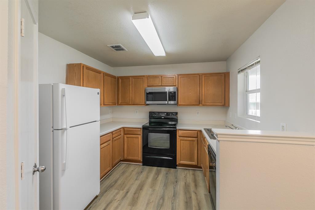 213 Cres Ridge Drive Fort Worth, TX 76140 - Photo 10 of 32 a kitchen with a refrigerator a stove top oven and cabinets
