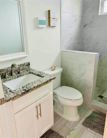 a bathroom with a granite countertop toilet sink and mirror