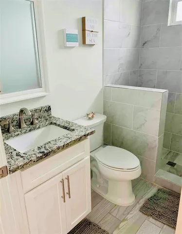 a bathroom with a granite countertop toilet sink and mirror