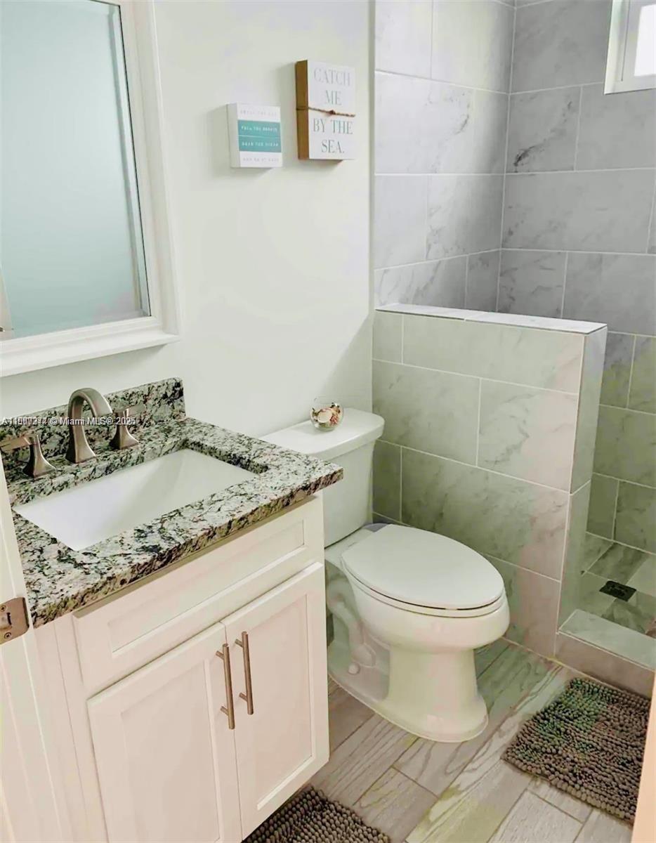 667 Southwest Cleveland Avenue, Unit 3 Stuart, FL 34994 - Photo 24 of 42 a bathroom with a granite countertop toilet sink and mirror