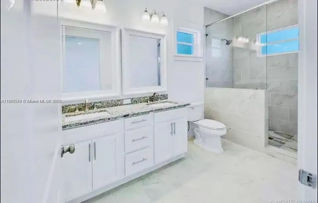 a bathroom with a granite countertop sink a toilet and shower
