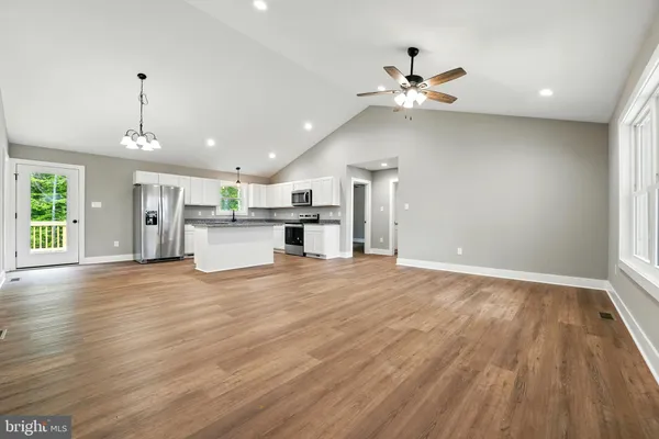 an empty room with wooden floor a ceiling fan and windows