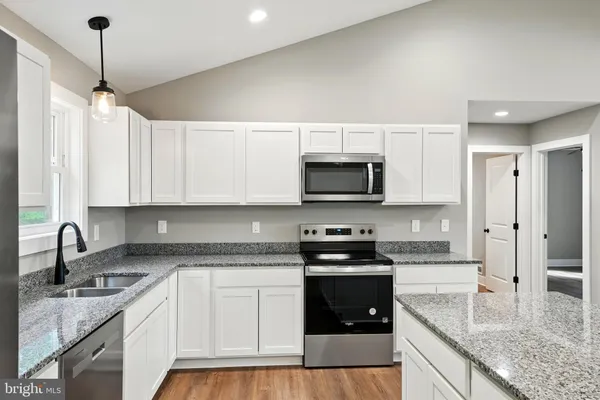 a kitchen with stainless steel appliances granite countertop a sink stove and white cabinets